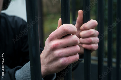 Closeup of hands behind a metallic fence - Captivity concept © pixarno