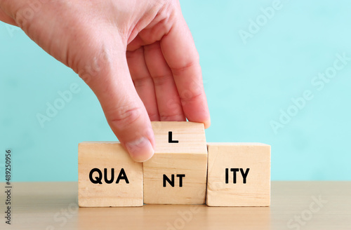 Concept image of quality management and performance with male hand picking wooden cube with text