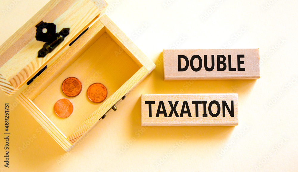 Double taxation symbol. Concept words Double taxation on wooden blocks on a beautiful white table white background. Wooden chest with coins. Business tax and double taxation concept, copy space. Double taxation symbol. Concept words Double taxation on wooden blocks on a beautiful white table white background. Wooden chest with coins. Business tax and double taxation concept, copy space.