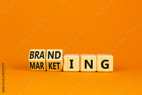 Branding and marketing symbol. Turned wooden cubes and changed the word Marketing to Branding. Beautiful orange table orange background, copy space. Business branding and marketing concept.