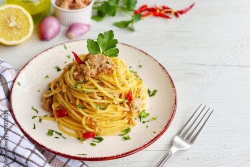 Obraz na płótnie Italian Traditional DishSpaghetti al tonno e limone,spaghetti with tuna in olive oil,lemon juice,shallots,olive oil,hot peppers and parleys on plate with white wood background
