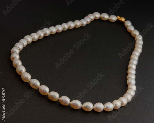 Pearl necklace on matte black background.
