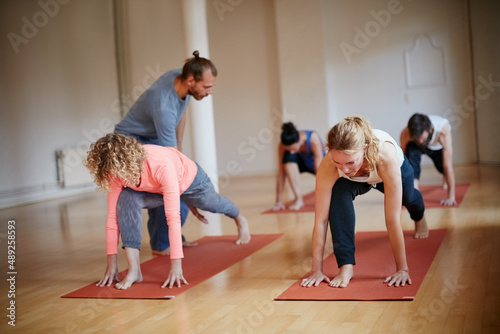 Your yoga instructor is the key to a successful class. Shot of a yoga instructor guiding one of his students.