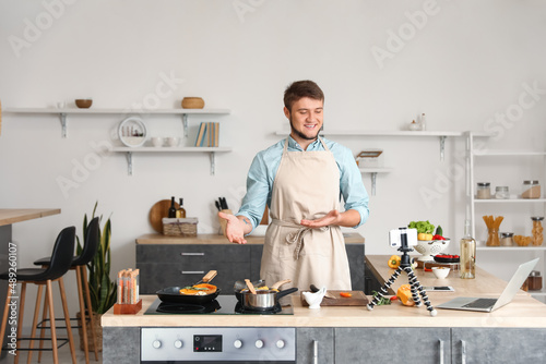Young man recording cooking video tutorial in kitchen