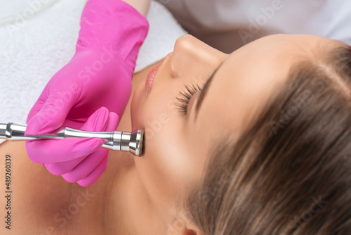 Cosmetologist makes procedure microdermabrasion on the face against acne and blackheads near the eyes. Women's cosmetology in the beauty salon.