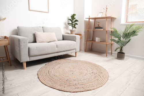 Obraz na plátně Trendy interior of light living room with comfortable sofa and wicker carpet