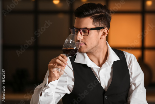 Young male sommelier tastin...
