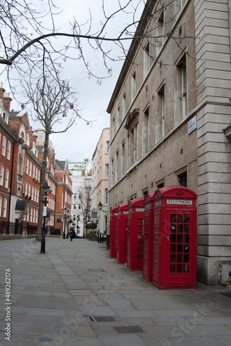 Red british telephone booth in a row on an empty street. London