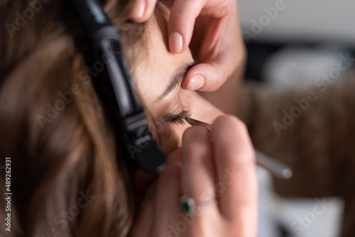 Make-up artist applies eyeliner to the girl's upper eyelid with a brush