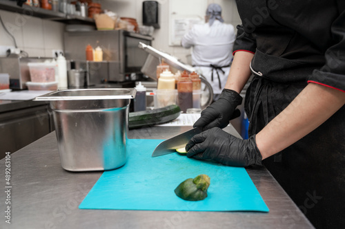 Female chef cutting vegetables at a commercial kitchen. High quality photo