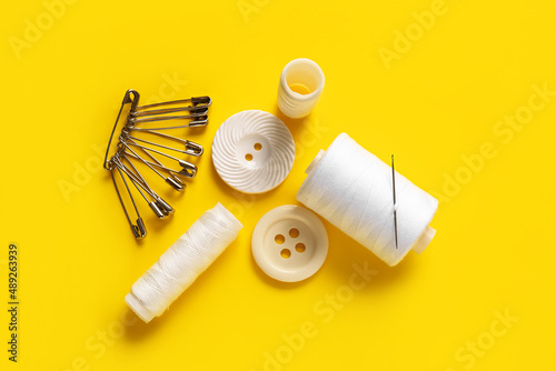 Thread spools with pins and buttons on yellow background