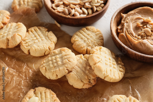 Parchment paper with tasty peanut cookies on table