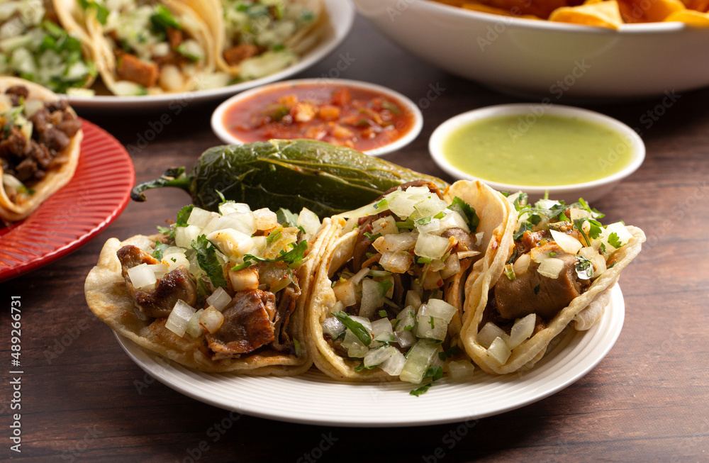 Three Delicious Buche Street Tacos in a Row on a Wooden Table Three Delicious Buche Street Tacos in a Row on a Wooden Table