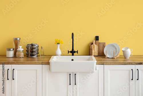 White counters with sink  kitchen utensils and food near yellow wall