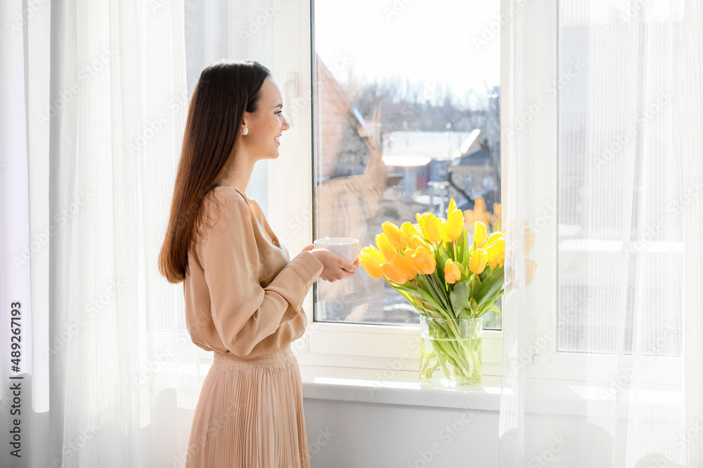 Pretty young woman drinking hot coffee near window Pretty young woman drinking hot coffee near window