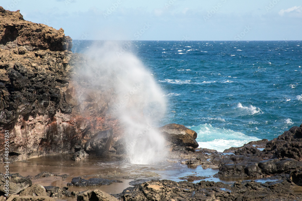 Blowhole with waves on rocky beach in Maui