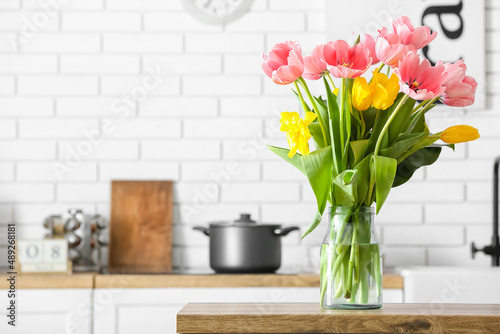 Beautiful tulips on wooden table in light kitchen