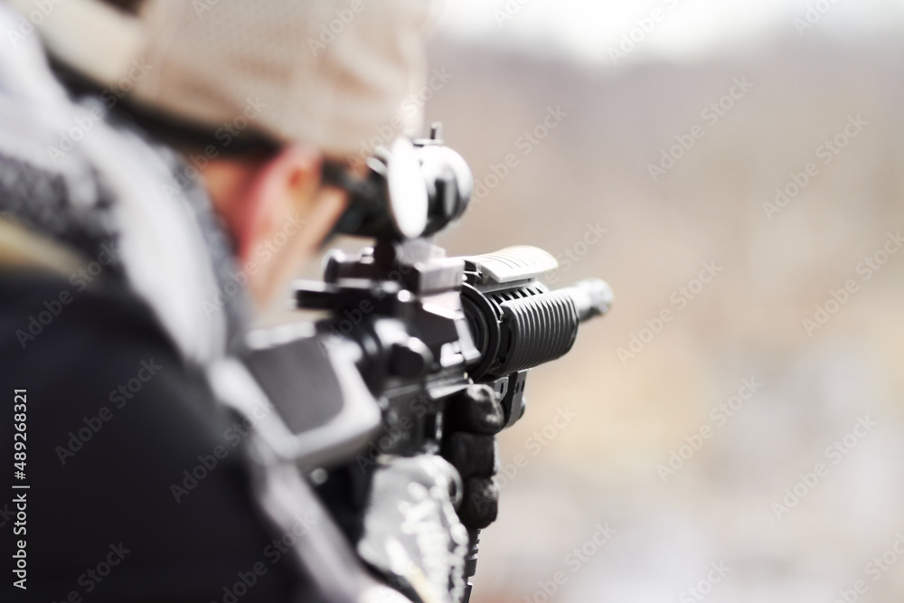 Focused on his target. Rearview of a snipper pointing his gun into the distance with copy space.