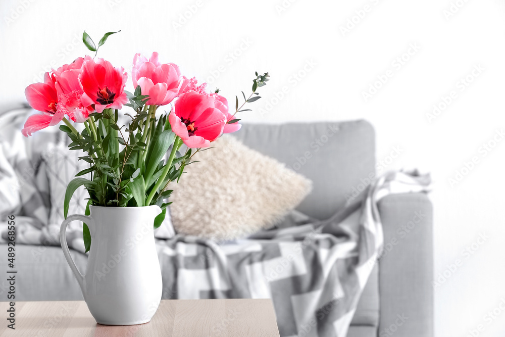 Vase with pink tulips on table in light living room