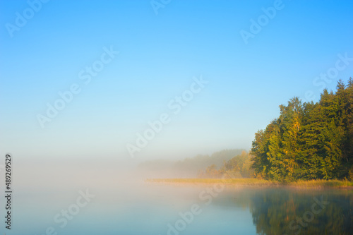 Autumn sunrise with mist on the lake surface.