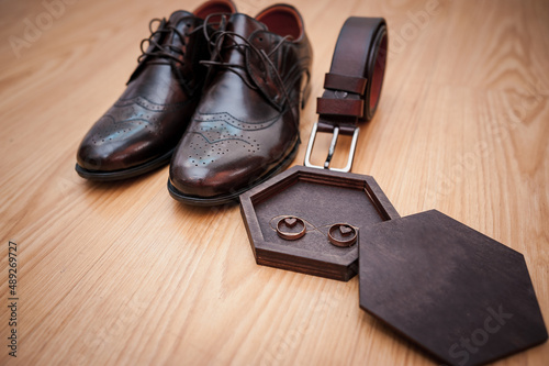 Leather men's shoes, a pair of gold wedding rings in a wooden box. Groom's accessories