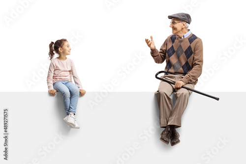 Grandfather sitting on a blank panel and talking to a little girl