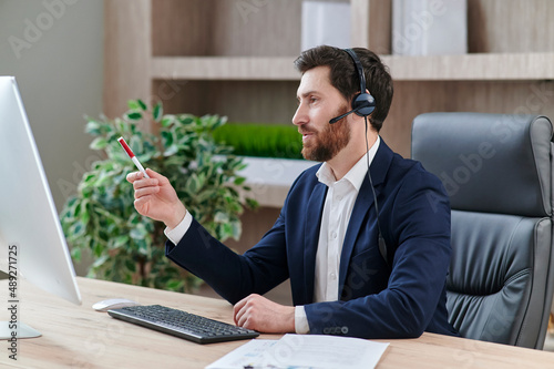 Representive practitioner leads online training wearing a suit and headset, with positive vibes and active gestures and explanations photo