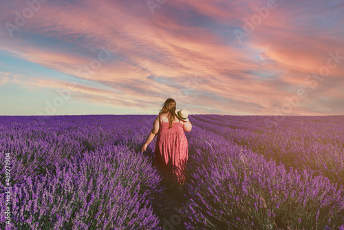 pretty plus size woman in a lavender field from the back.