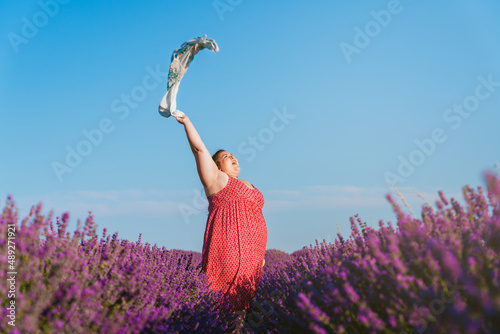 Beautiful plus size woman posing in a field full of purple flowers