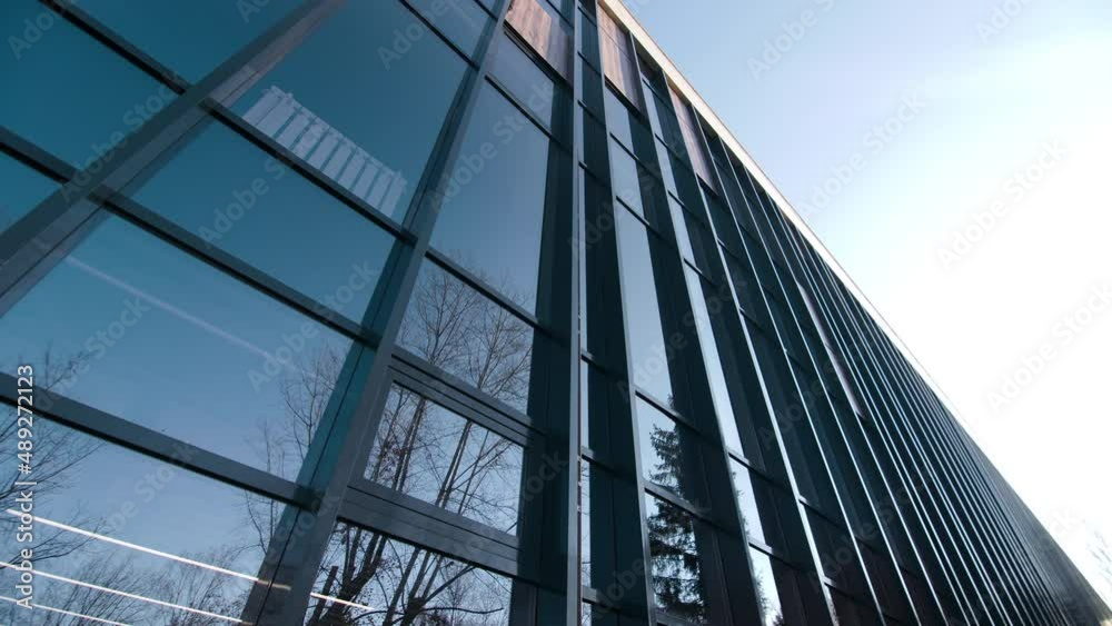 Motion past stylish office building with dark glass facade on modern city street at sunset light closeup. Urban architecture Motion past stylish office building with dark glass facade on modern city street at sunset light closeup. Urban architecture