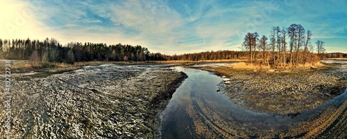 Panorama.View from above on the fish pond with drained water and flowing river among the forest of Podlasie on a sunny ,winter day.