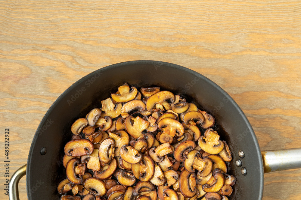 Pan-fried Champignon mushrooms on a frying pan. Brown edible fungi slices prepared. Pan-fried Champignon mushrooms on a frying pan. Brown edible fungi slices prepared.
