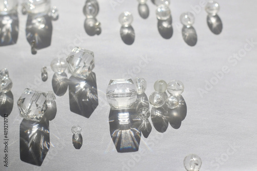 Various transparent beads on white background, illuminated by sunlight and reflectiing light. Selective focus. photo