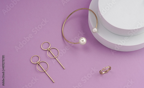 Top view of golden jewelries on round white podium on purple background with copy space