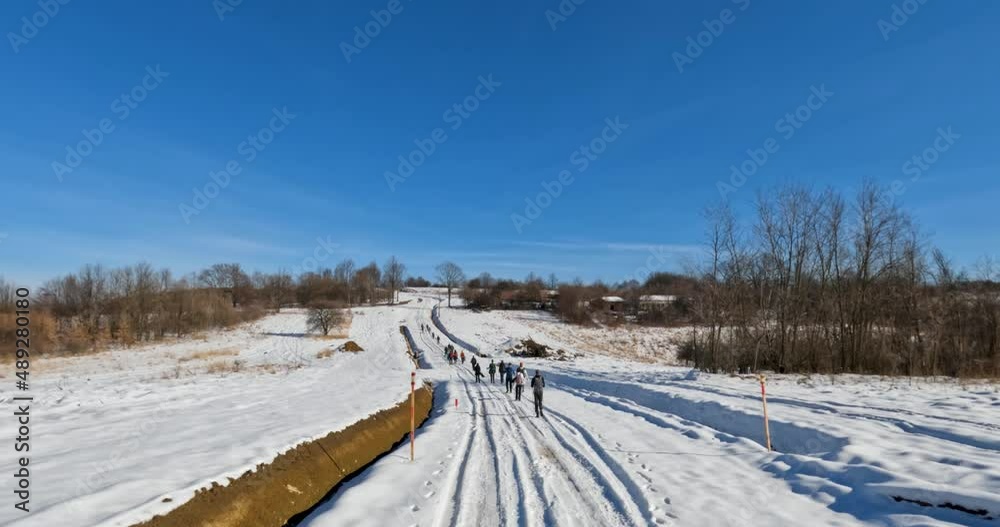 Winter nature landscape. Group of people hiking on trail at snowy road. Winter adventure journey. Clear blue sky. Back view of hikers.	