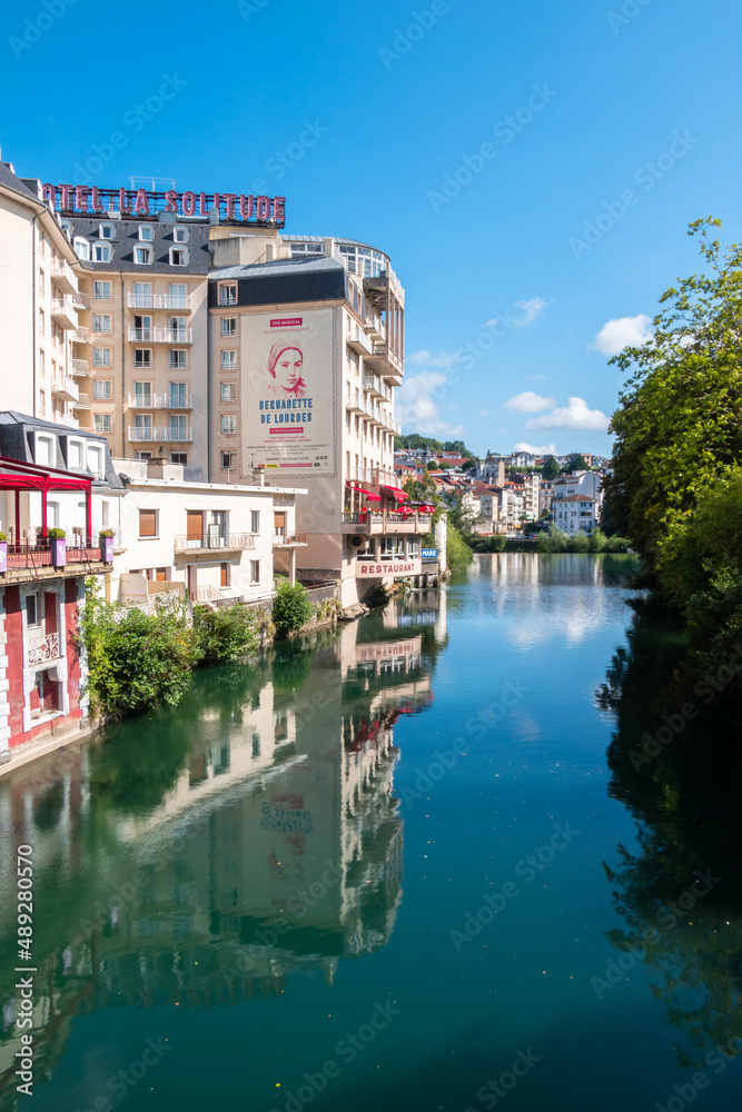 Obraz premium Lourdes, France - August 28, 2021: Cityscape of Lourdes with hotels and residential buildings on the banks of the river Ousse