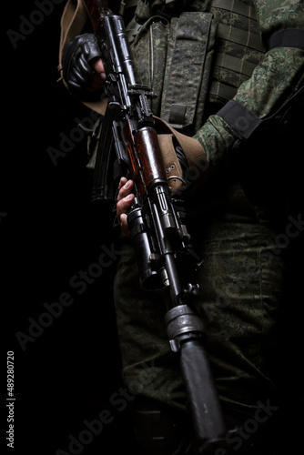 Closeup photo of man's hand holding machine gun. Man is wearing military uniform.