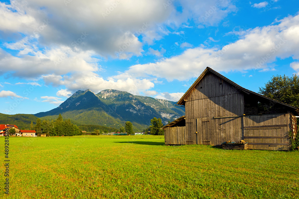 Obraz premium Beautiful Austrian Landscape with agricultural field, old barn and mountains. Bad Goisern, Upper Austria. 