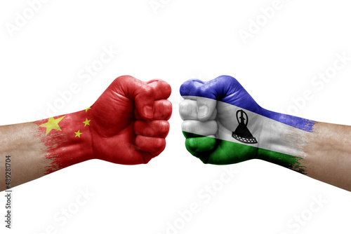 Two hands punch to each others on white background. Country flags painted fists, conflict crisis concept between china and lesotho