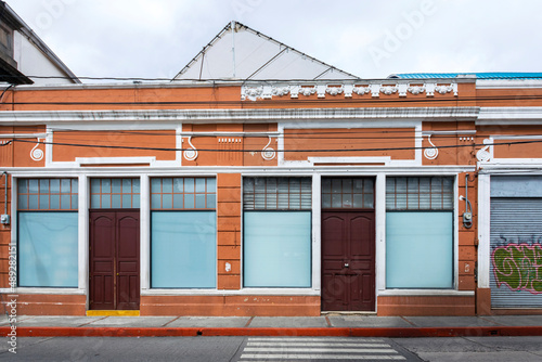Guatemala – October 10, 2021. Facade of private house in Guatemala City, light at dawn and clear sky in commercial area and old Latin American capital, anti-seismic architecture.