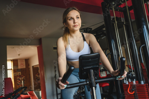 one woman young adult female training at the gym in day sitting riding on the spinning bike bicycle cardio workout exercise real people copy space