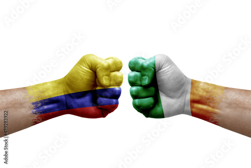 Two hands punch to each others on white background. Country flags painted fists, conflict crisis concept between colombia and ireland