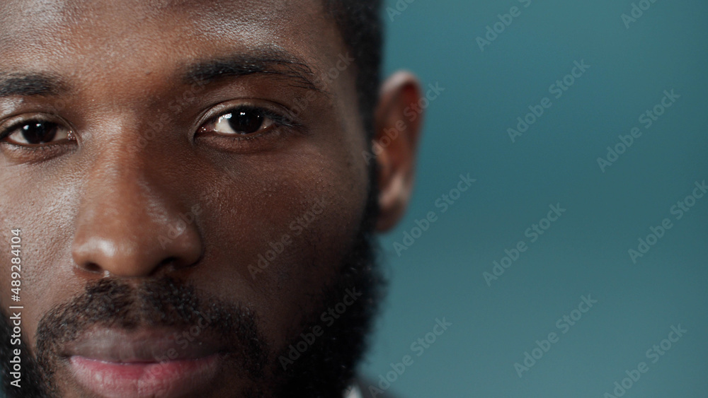 Fototapeta premium A young black bearded man in a official suit blinks and looks at the camera