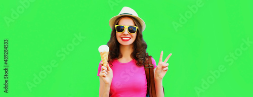 Portrait of happy smiling young woman with ice cream wearing summer straw hat on green background © rohappy