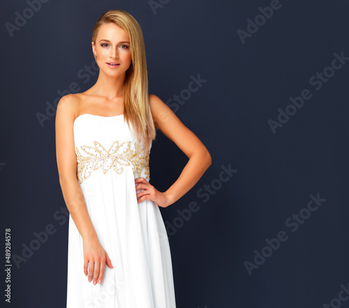 Stunning young model posing in evening gown. Portrait of stunning young model posing in evening gown on black background.