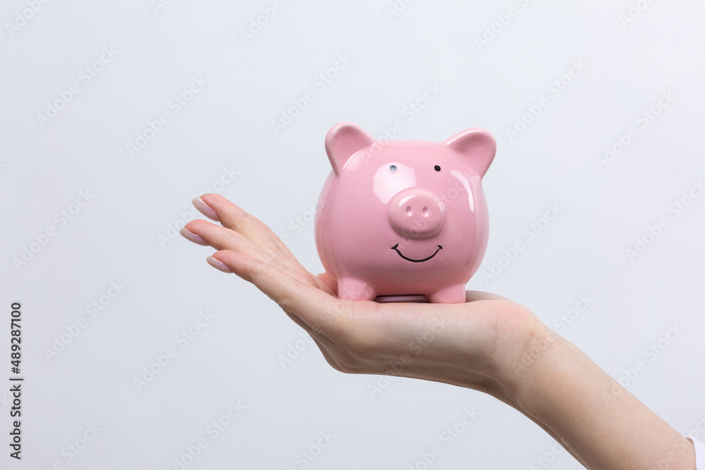 3d pink piggy bank in the beautiful hands of a girl..Close-up photo on a white background.