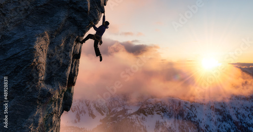 Adult adventurous man Rock Climbing a steep rocky cliff. Extreme adventure composite. 3d rendering mountain artwork. Aerial background landscape from British Columbia, Canada. Sunset Sky