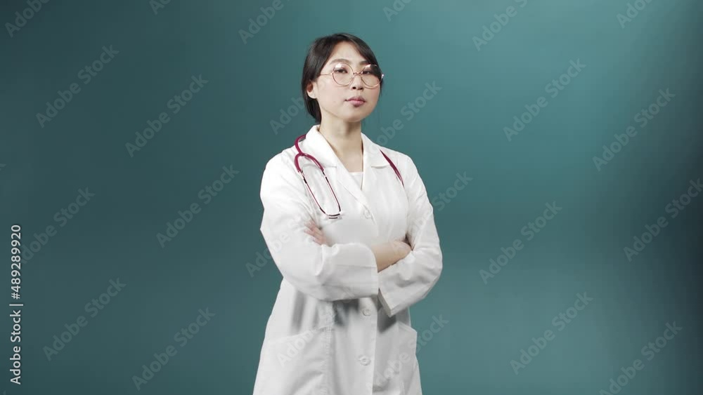 A serious doctor in a medical uniform is crossing her arms and looking at the camera A serious doctor in a medical uniform is crossing her arms and looking at the camera