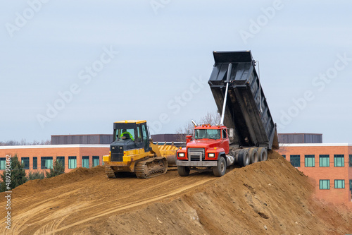 A large yellow dump truck unloads the sand