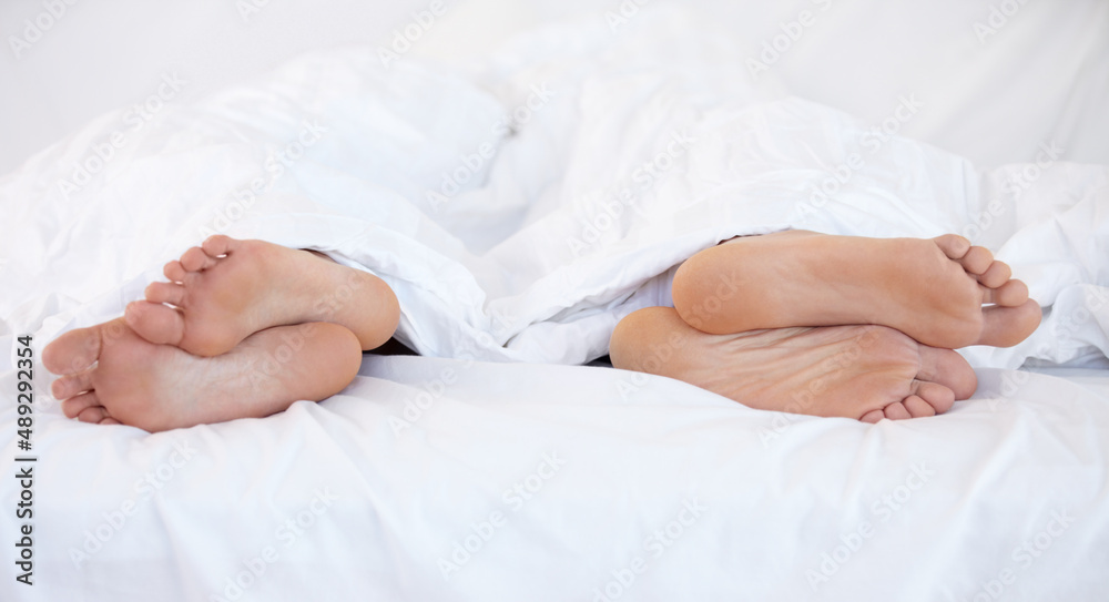 Growing apart.... Cropped image of the feet of two people in bed facing in two different directions. Growing apart.... Cropped image of the feet of two people in bed facing in two different directions.